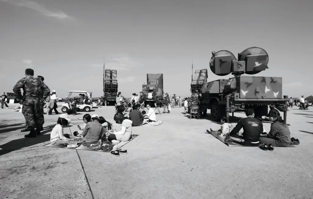 Eine Familie bei einem Picknick neben Militärfahrzeugen auf einer Ausstellung für Militärausrüstung