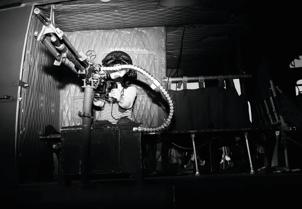 Kind sitzt auf einer Ausstellung für Militärausrüstung an einem Maschinengewehr.